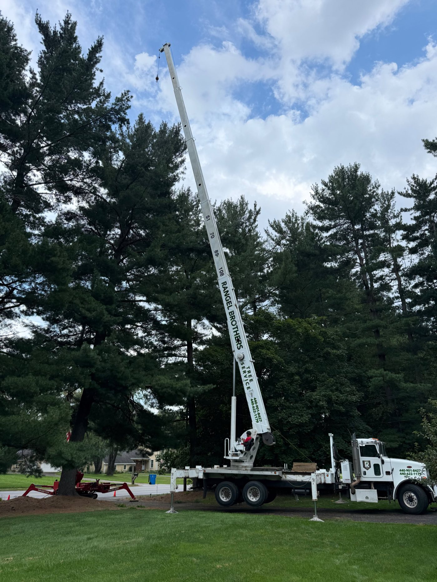 Rangel Brothers crane truck with boom marked to 108 feet raised into tall pines Rangel Brothers crane truck with boom marked to 108 feet raised into tall pines