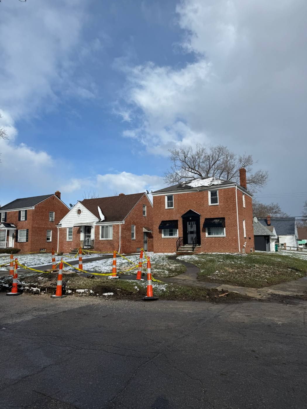 Brick houses with the fallen tree removed and the area coned off
